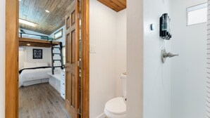 A bedroom with a bunk bed, a wooden ceiling, and a white wall with a framed picture. - Tiny 2- Sleeping Elephant (Bellvue)