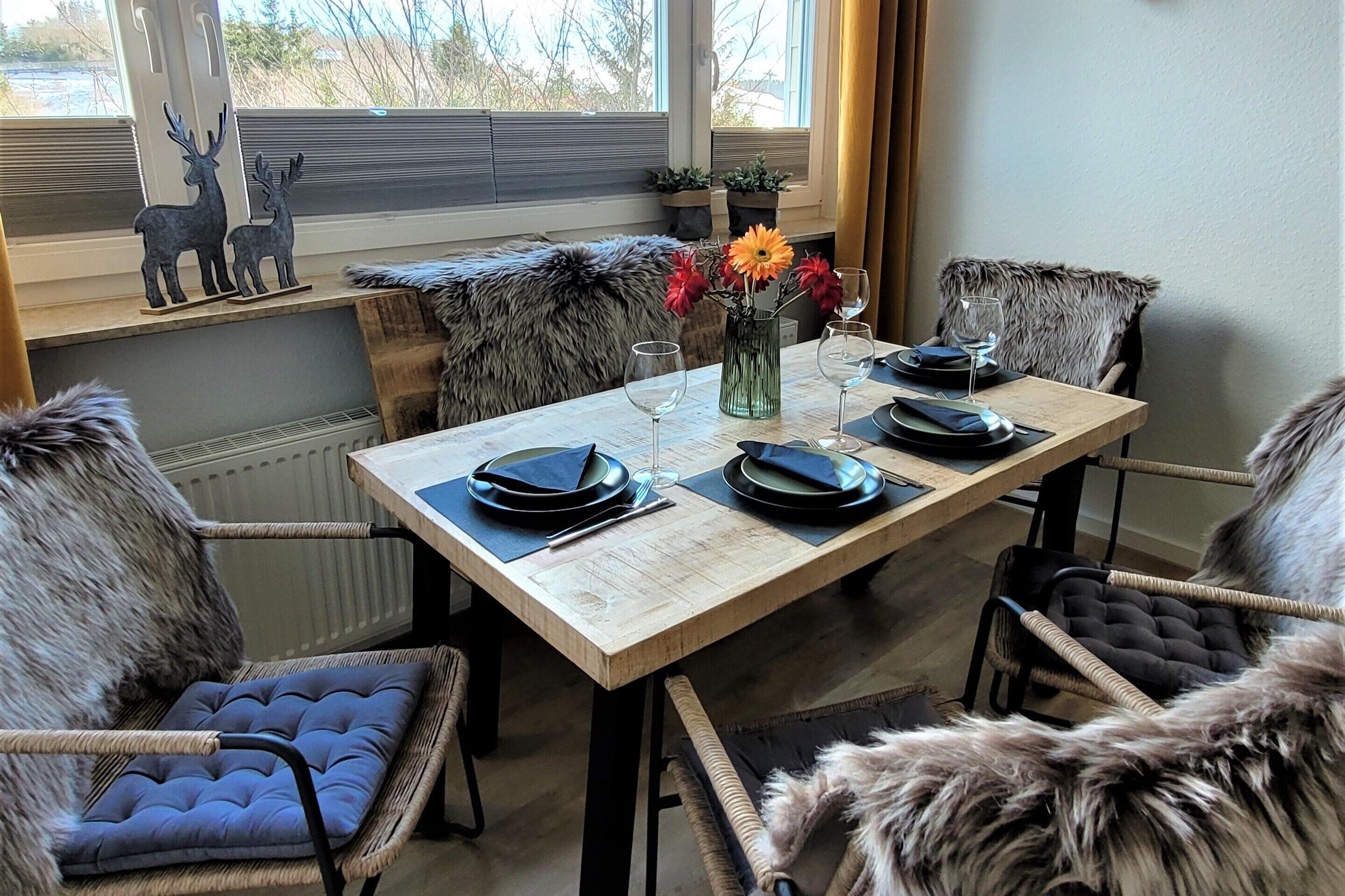 A dining table set with plates, glasses, and a vase of flowers.
