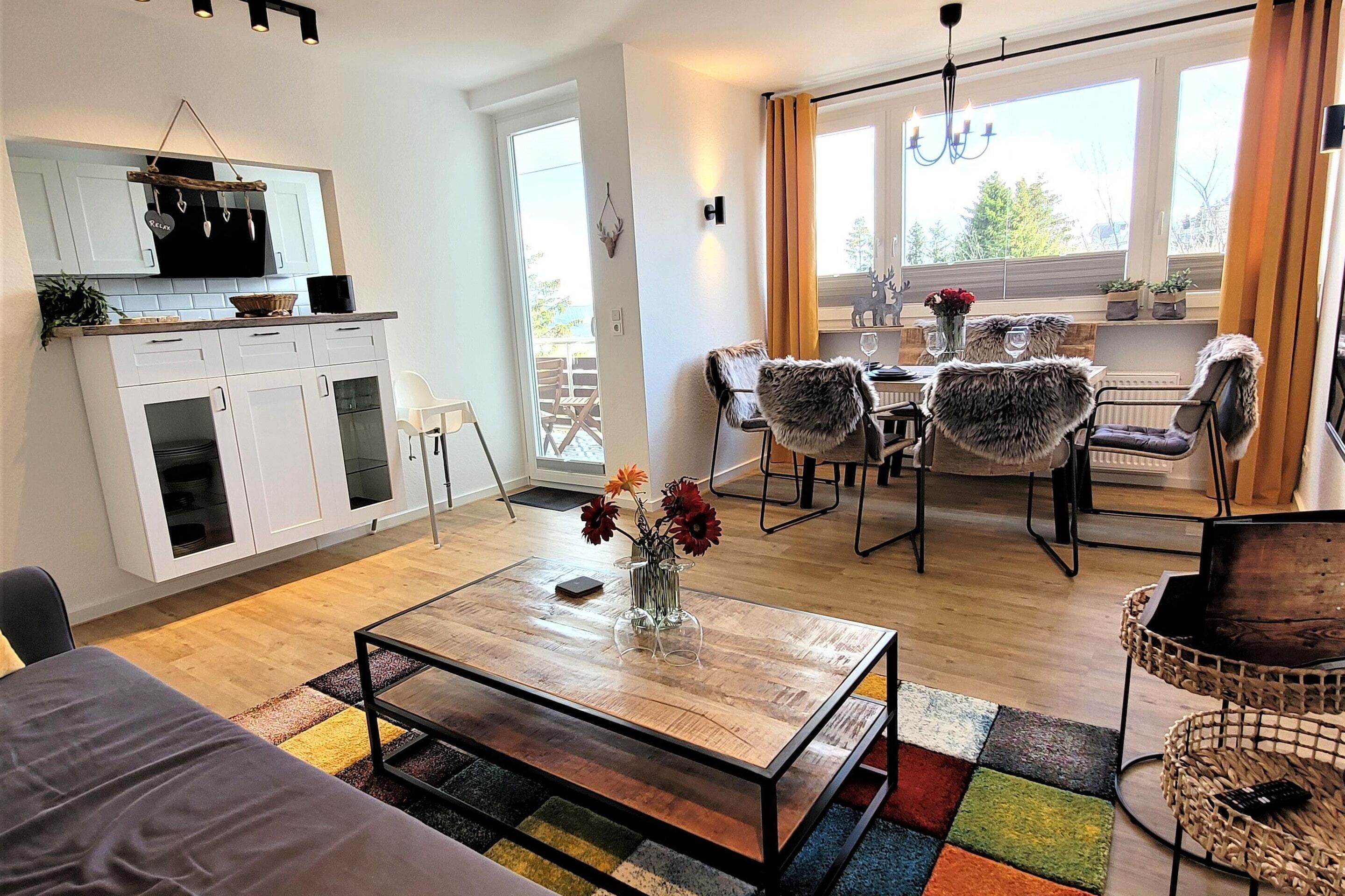 A modern living space with a kitchen, dining area, and a large window.