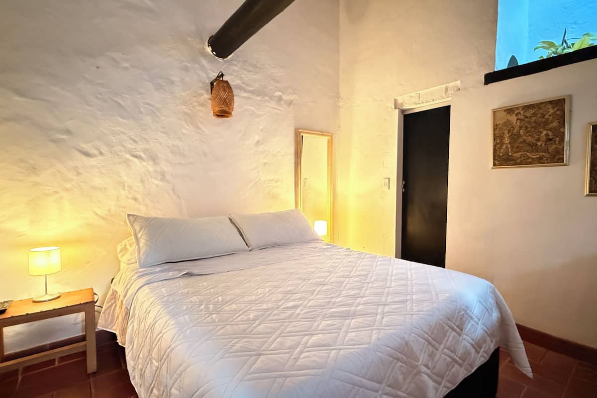 A bedroom with a bed, a nightstand, a lamp, and two doors.