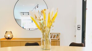 A dining area with a round table, black chairs, and a vase with dried flowers.