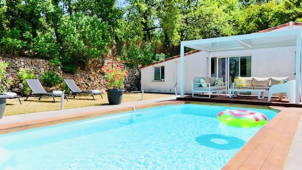A swimming pool with lounge chairs and a covered seating area.