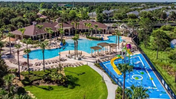 Un resort con una gran piscina, un tobogán acuático y una cancha de tenis.