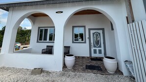 A two-story house with a covered porch, two large windows, and a door with a decorative glass panel. - Luxurious and Charming 3-bedroom house with WiFi, AC in delightful George Town (George Town)