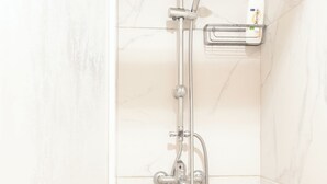 Une douche équipée d’un pommeau de douche à main, d’une brosse à récurer à main et d’un robinet mural.