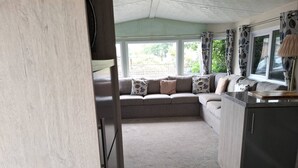 Una sala acogedora con un conjunto de sofás, un mueble de madera y una ventana con cortinas.