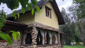 Ein zweistöckiges Haus mit Naturstein-Fassade und geneigtem Dach.