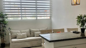 A modern kitchen with a central island, a sofa, and a dining area. - Ducassi Rooftop Pool Beach Suites (Punta Cana)