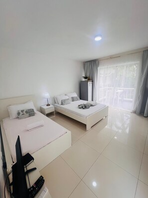A hotel room with a bed, a desk, a TV, and a balcony with curtains. - Paradise Beach Suites Sol Caribe (Punta Cana)