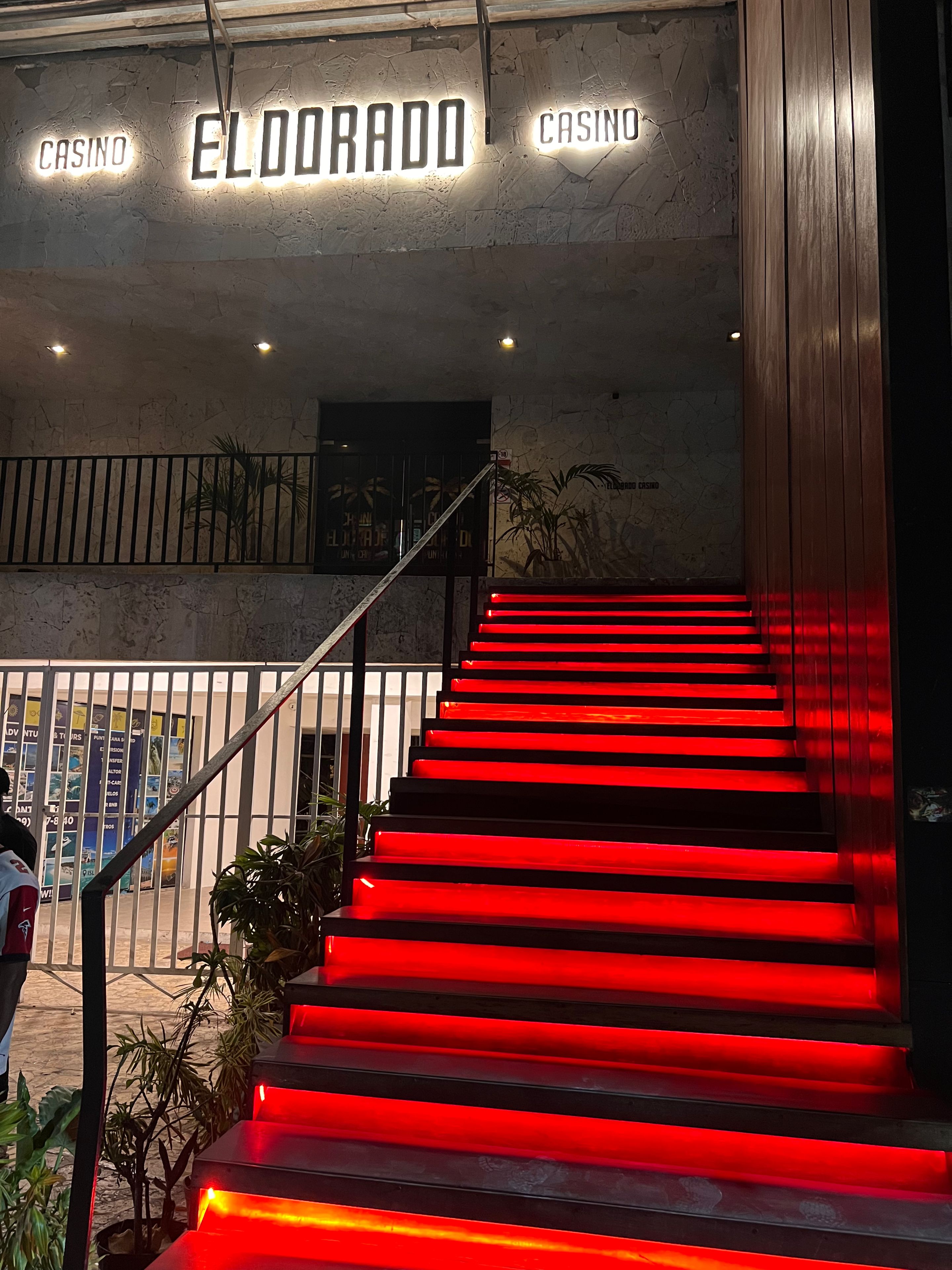 Een trap met rode verlichting die naar de ingang van een gebouw leidt, waarop 'EL DORADO CASINO' staat.