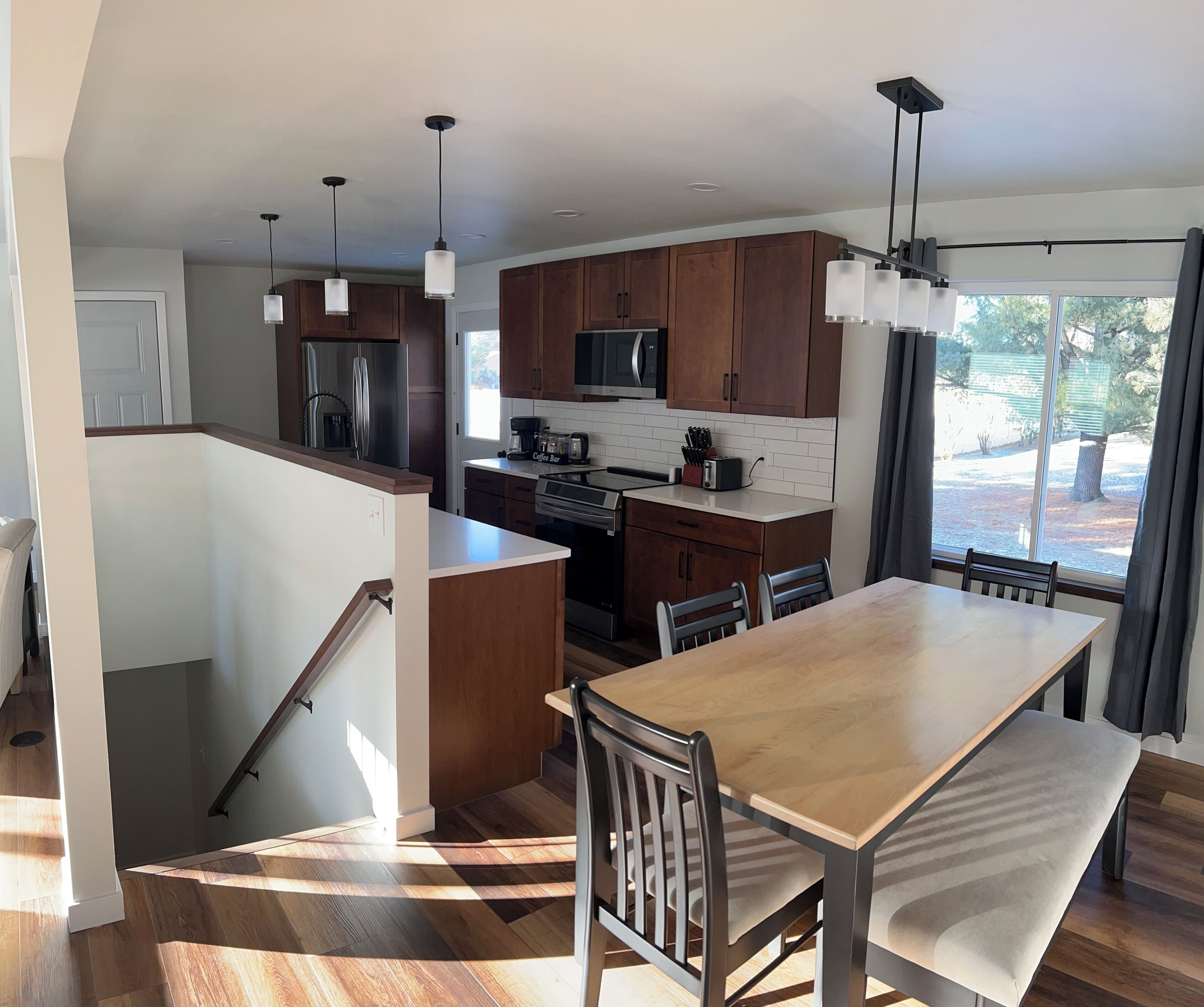 Une cuisine moderne avec des meubles en bois, des appareils en acier inoxydable et des luminaires suspendus.