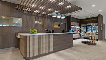 Una moderna recepción de hotel con un mostrador de madera, un área de snacks y un mostrador visible.