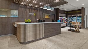 A modern hotel reception with a wooden reception desk, a snack area, and a visible counter. - Home2 Suites By Hilton Lebanon (Lebanon)