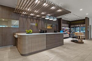 A modern hotel reception with a wooden reception desk, a snack area, and a visible counter.
