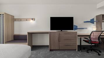 Ein Hotelzimmer mit Bett, Schreibtisch mit Fernseher, Stuhl und Kleiderschrank.