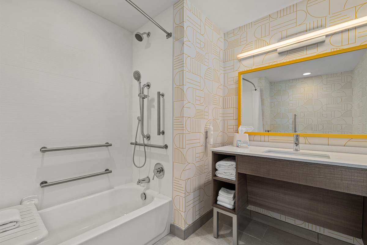A modern bathroom with a bathtub, shower, and vanity with a mirror.