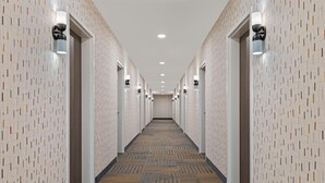 A hotel hallway with patterned walls, recessed lighting, and a carpeted floor. - Home2 Suites By Hilton Lebanon (Lebanon)