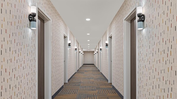 A hotel hallway with patterned walls, recessed lighting, and a carpeted floor. - Home2 Suites By Hilton Lebanon (Lebanon)