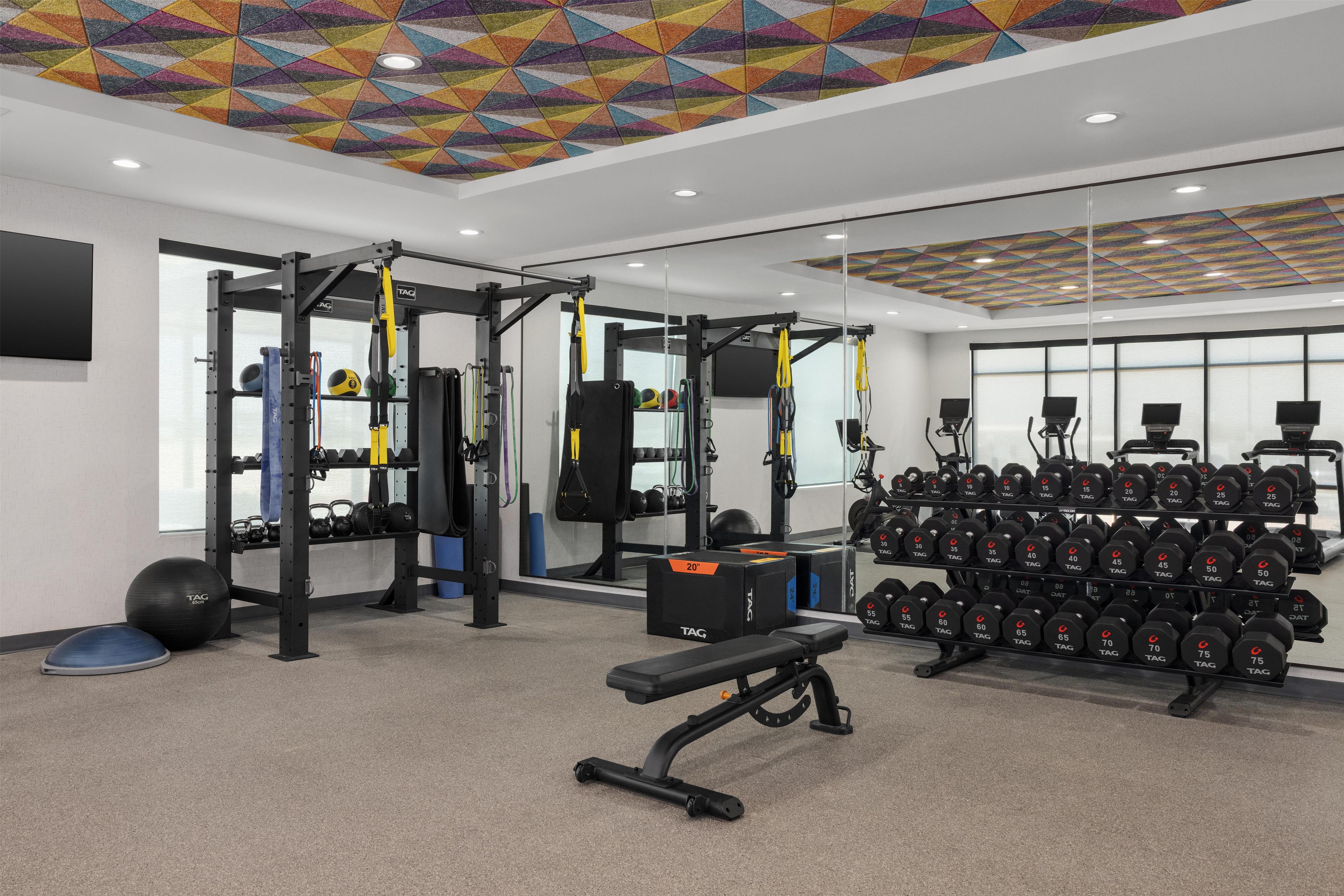 Un gimnàs amb equipament de musculació, pilotes d'exercici i halteres.