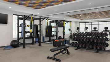Un gimnasio con equipo de levantamiento de pesas, pelotas de ejercicio y mancuernas.