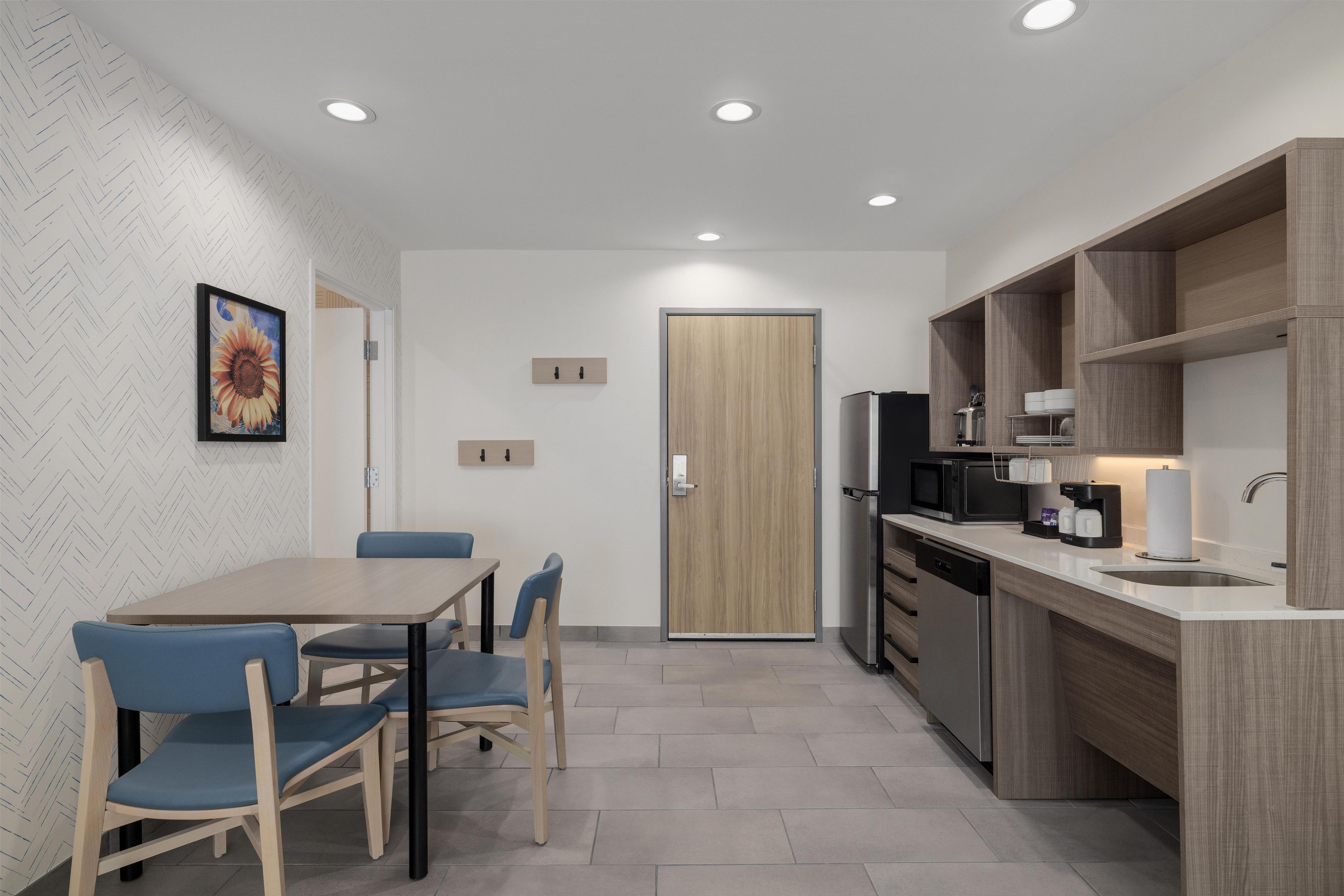 Une cuisine moderne avec un coin repas, dotée d’une porte en bois, d’appareils électroménagers intégrés et d’un mur orné d’un motif en chevrons.