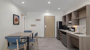 Une cuisine moderne avec un coin repas, dotée d’une porte en bois, d’appareils électroménagers intégrés et d’un mur orné d’un motif en chevrons.