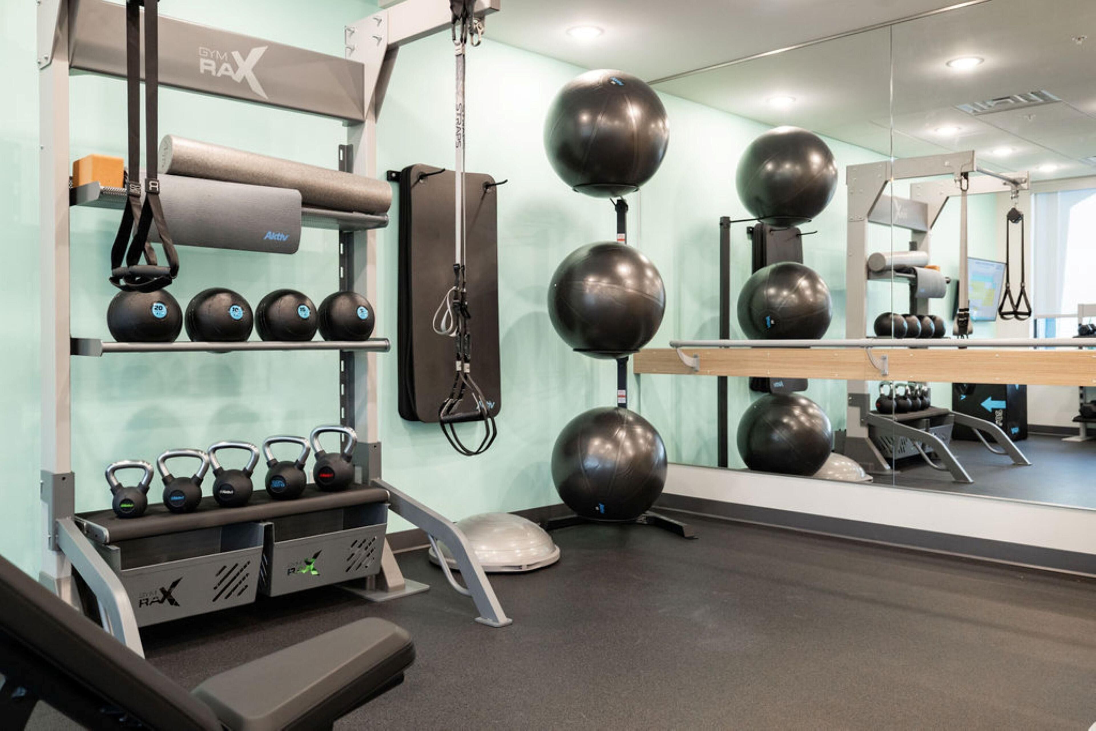 Un gimnasio con pesas rusas, balones de ejercicio y una cinta de correr.