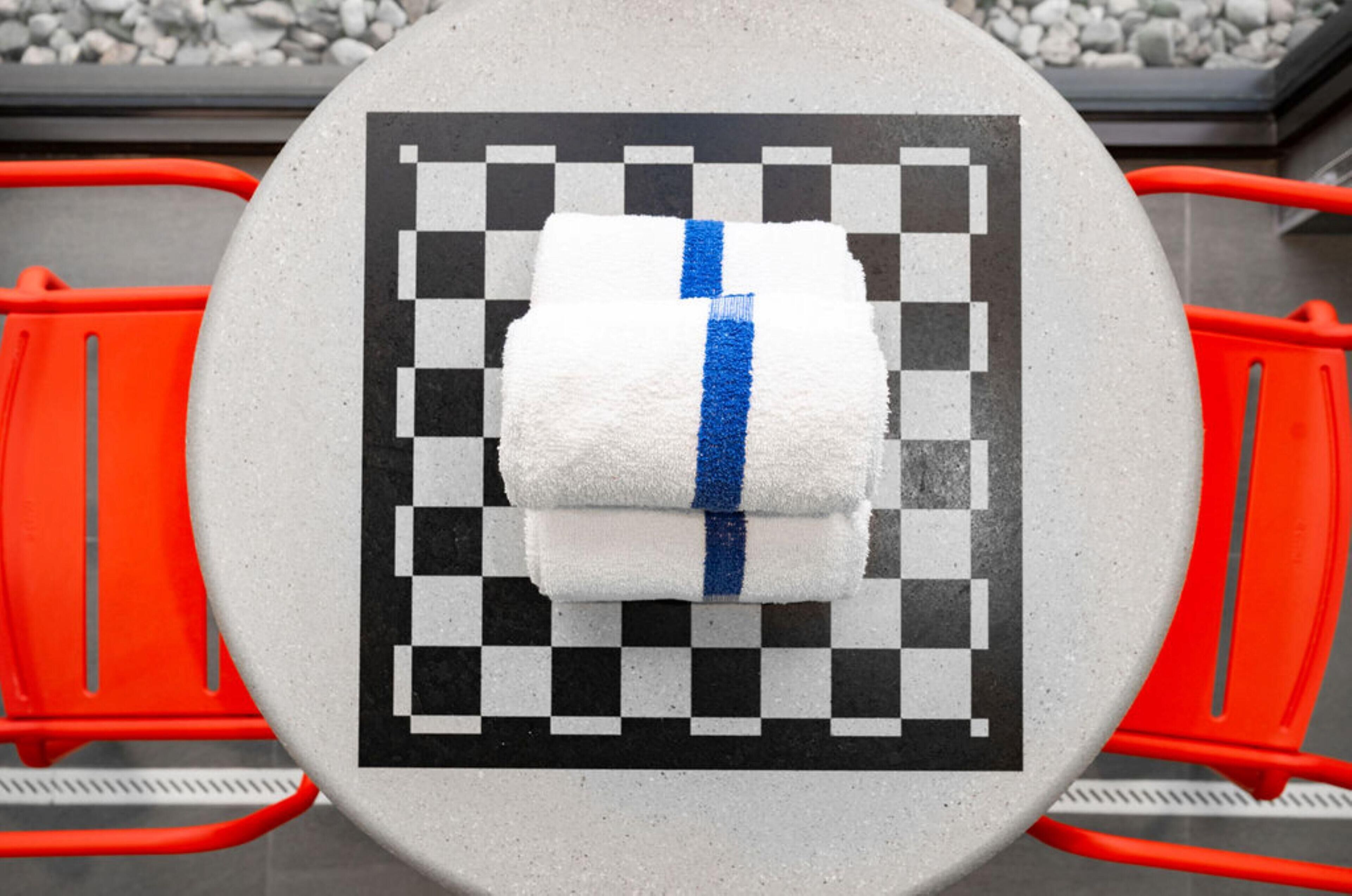 A round table with a checkered pattern and a towel with a blue stripe.