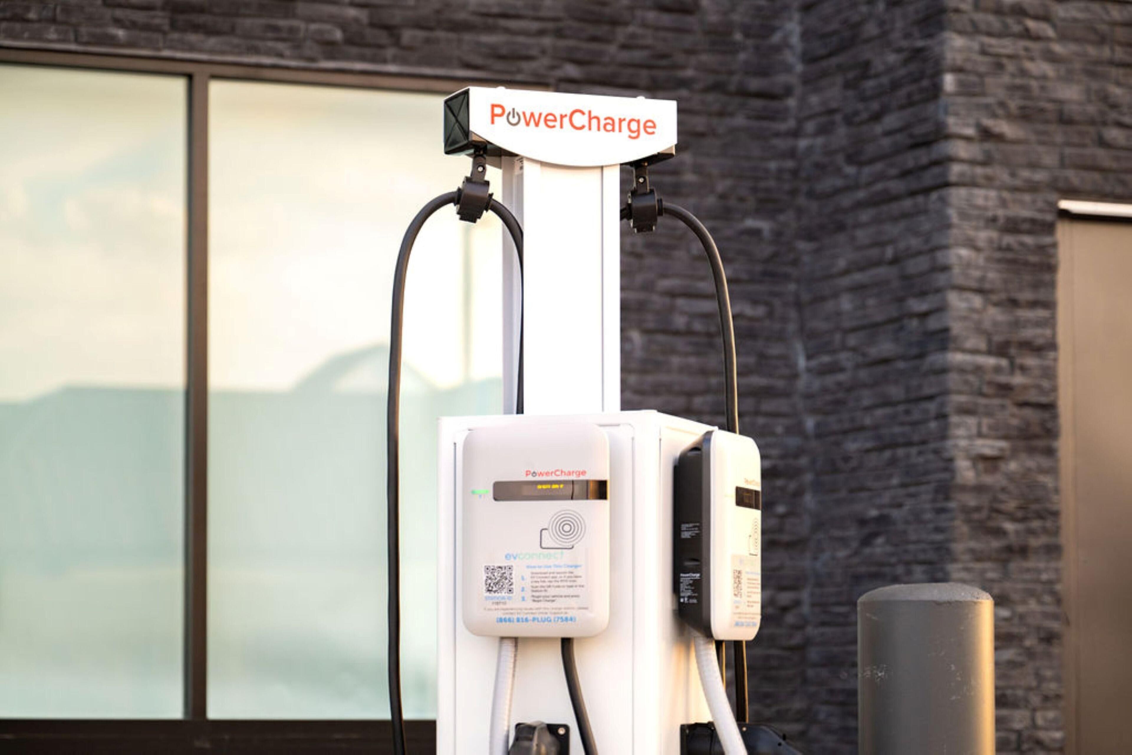 Una estación de carga para vehículos eléctricos PowerCharge, con diseño blanco y negro, un código QR y un enchufe.