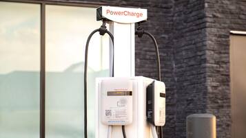 Una estación de carga para vehículos eléctricos PowerCharge, con diseño blanco y negro, un código QR y un enchufe.