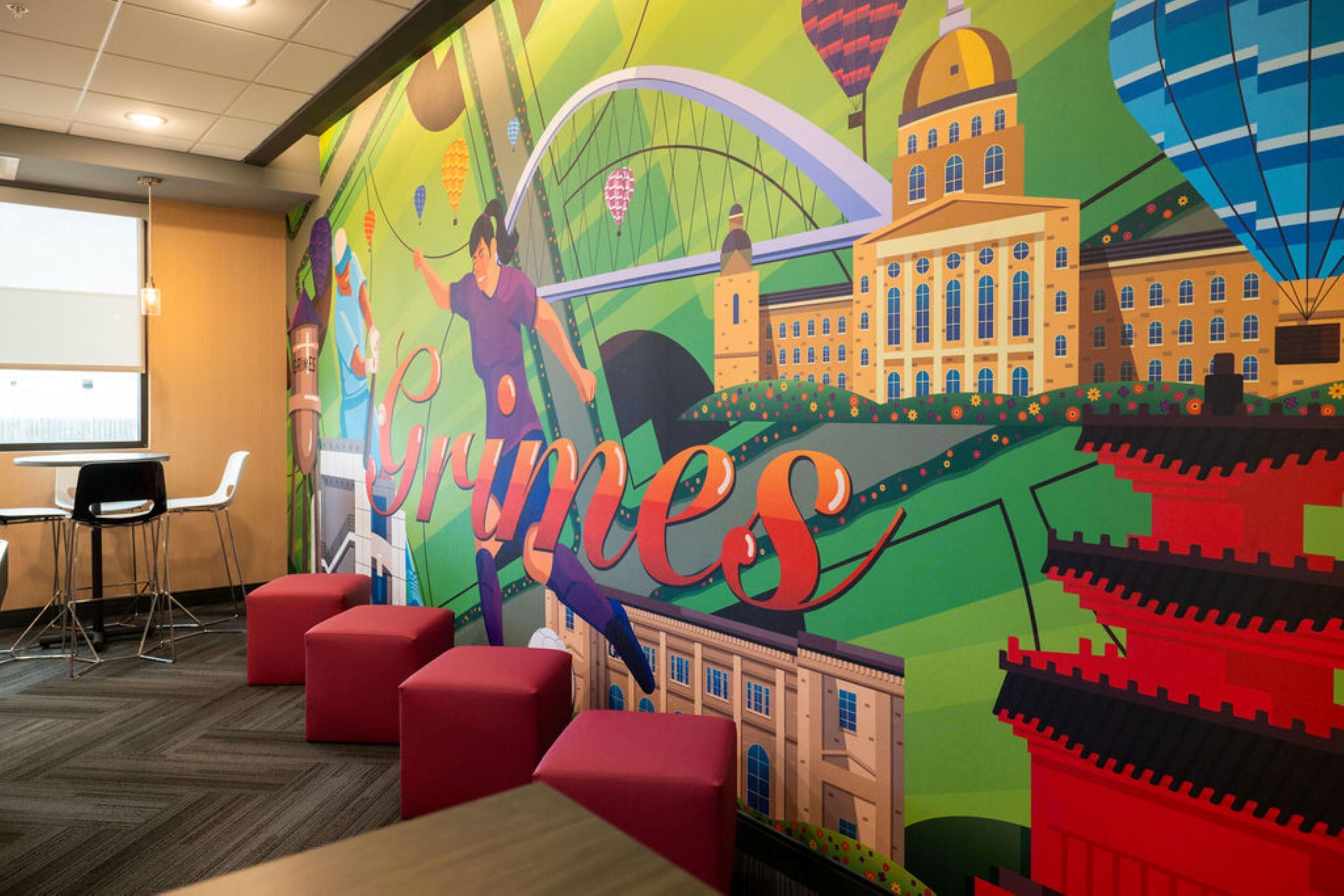 A conference room with a colorful mural, red seating, and a projector screen.