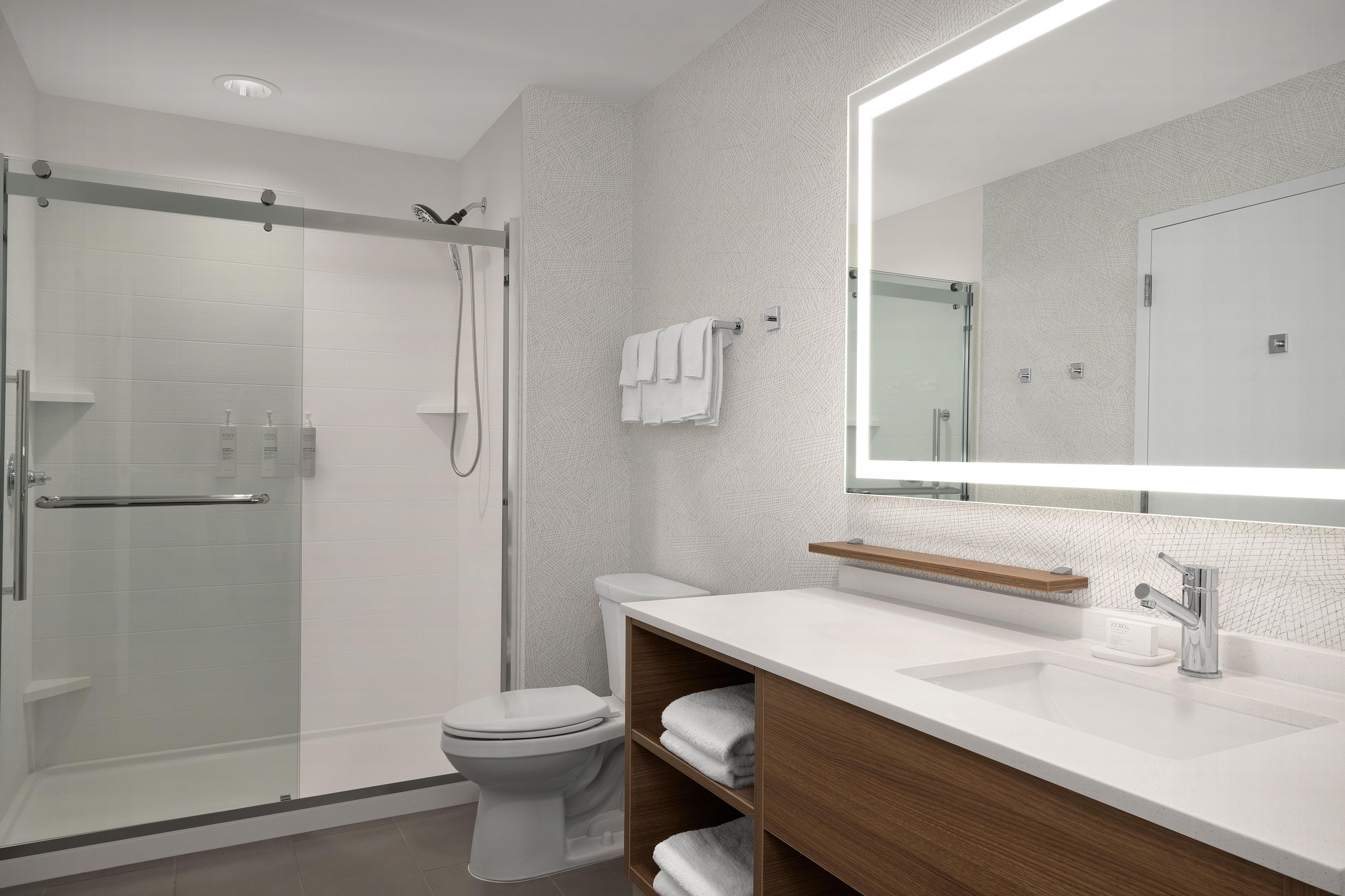 Une salle de bain moderne avec une douche à parois de verre, des toilettes et un meuble-lavabo avec un miroir.