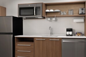 A modern kitchen with a stainless steel refrigerator, a microwave, a coffee maker, and wooden cabinets. - Home2 Suites By Hilton Hickory (Hickory)