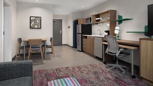 A modern kitchen with a microwave, refrigerator, and dining area with chairs and a table.