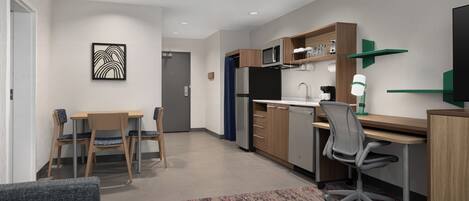 Eine moderne Küche mit Mikrowelle, Kühlschrank und Essbereich mit Stühlen und Tisch.