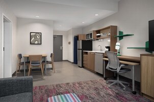 Una cocina moderna con microondas, refrigerador y comedor con sillas y mesa.