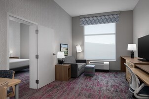 A hotel room with a bed, a desk, a chair, a lamp, a TV, and a window with a view.