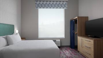 A hotel room with a bed, a television, a wardrobe, and a window with a view.