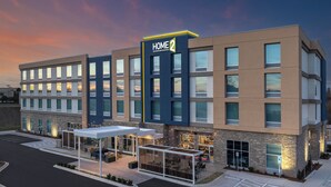 A modern hotel with a 'HOME 2' sign, outdoor seating, and a parking lot. - Home2 Suites By Hilton Hickory (Hickory)