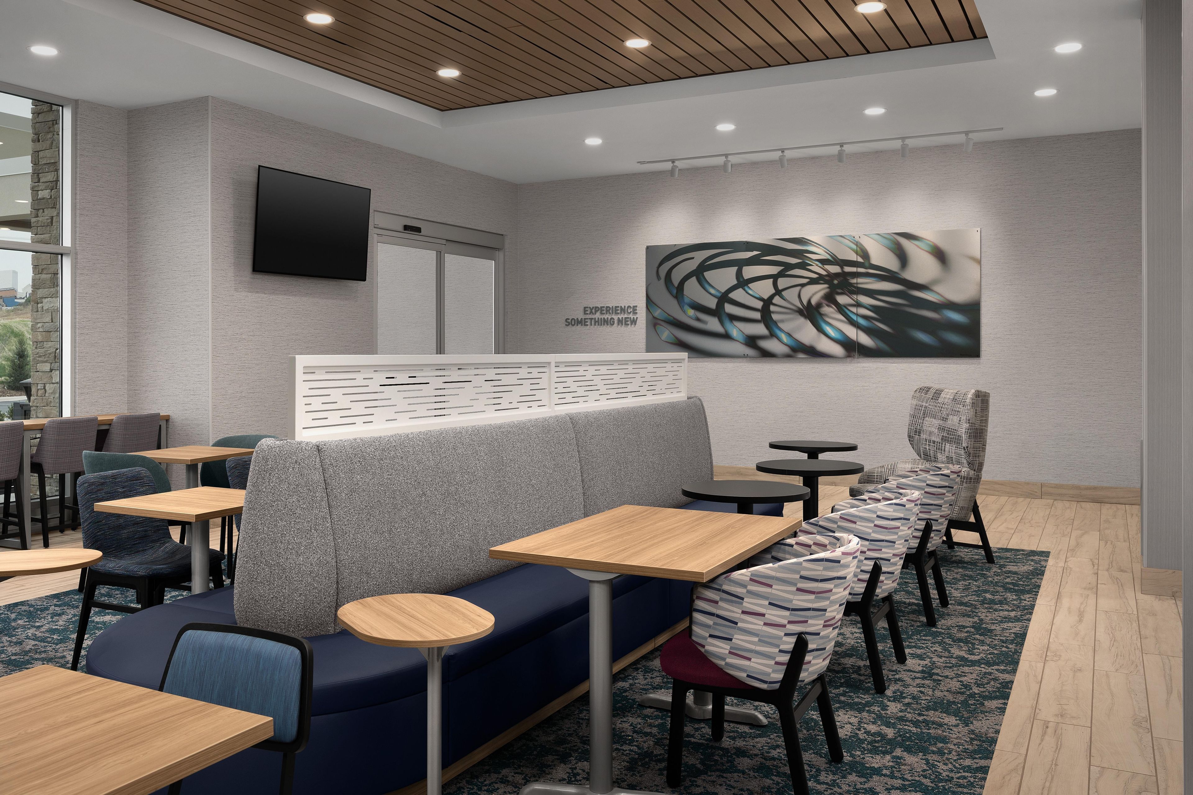 A modern cafe interior with seating arrangements, a flat-screen TV, and a wall-mounted artwork.