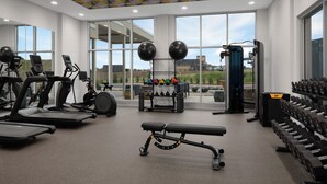 A gym with treadmills, a bench press, dumbbells, and a squat rack. - Home2 Suites By Hilton Hickory (Hickory)