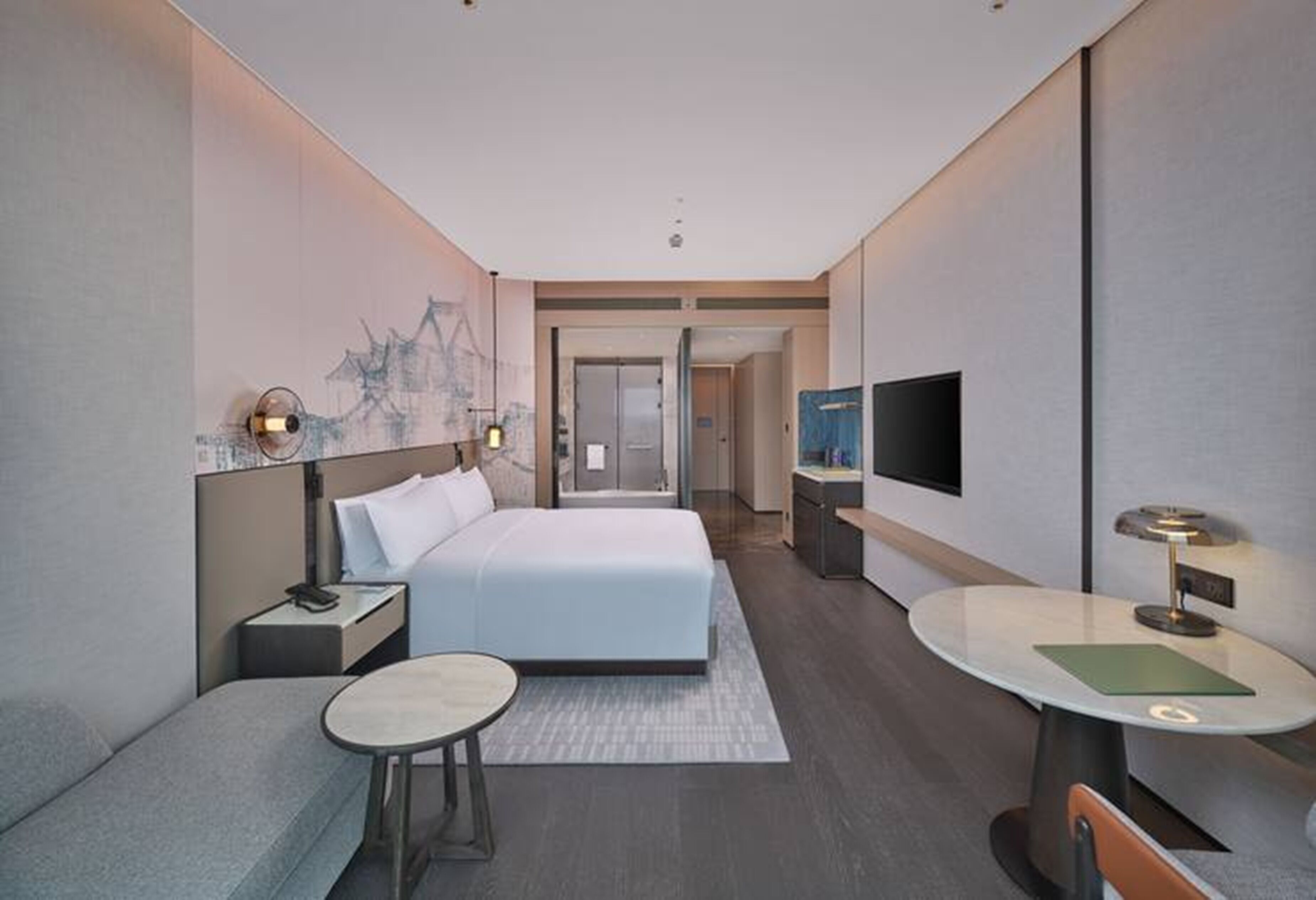 Una habitación de hotel moderna con cama, escritorio, televisor y zona de estar.