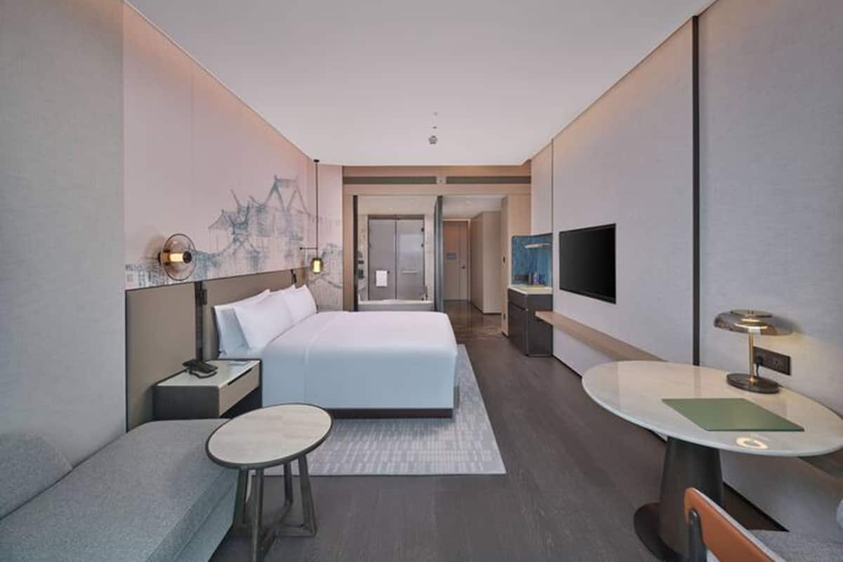 Ein modernes Hotelzimmer mit Bett, Schreibtisch, Fernseher und Sitzgelegenheit.