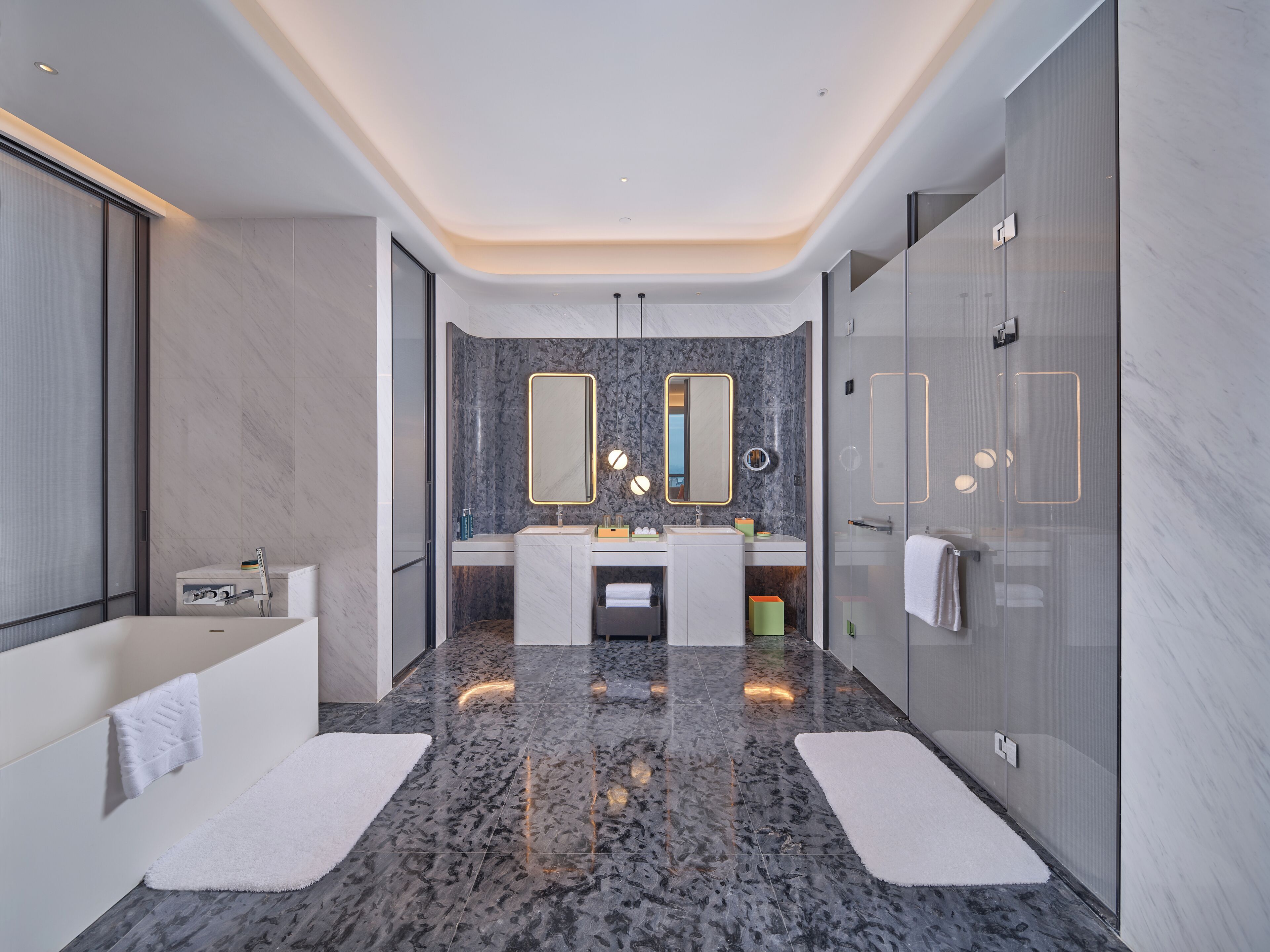A modern bathroom with a bathtub, two sinks, a large mirror, and a glass shower enclosure.