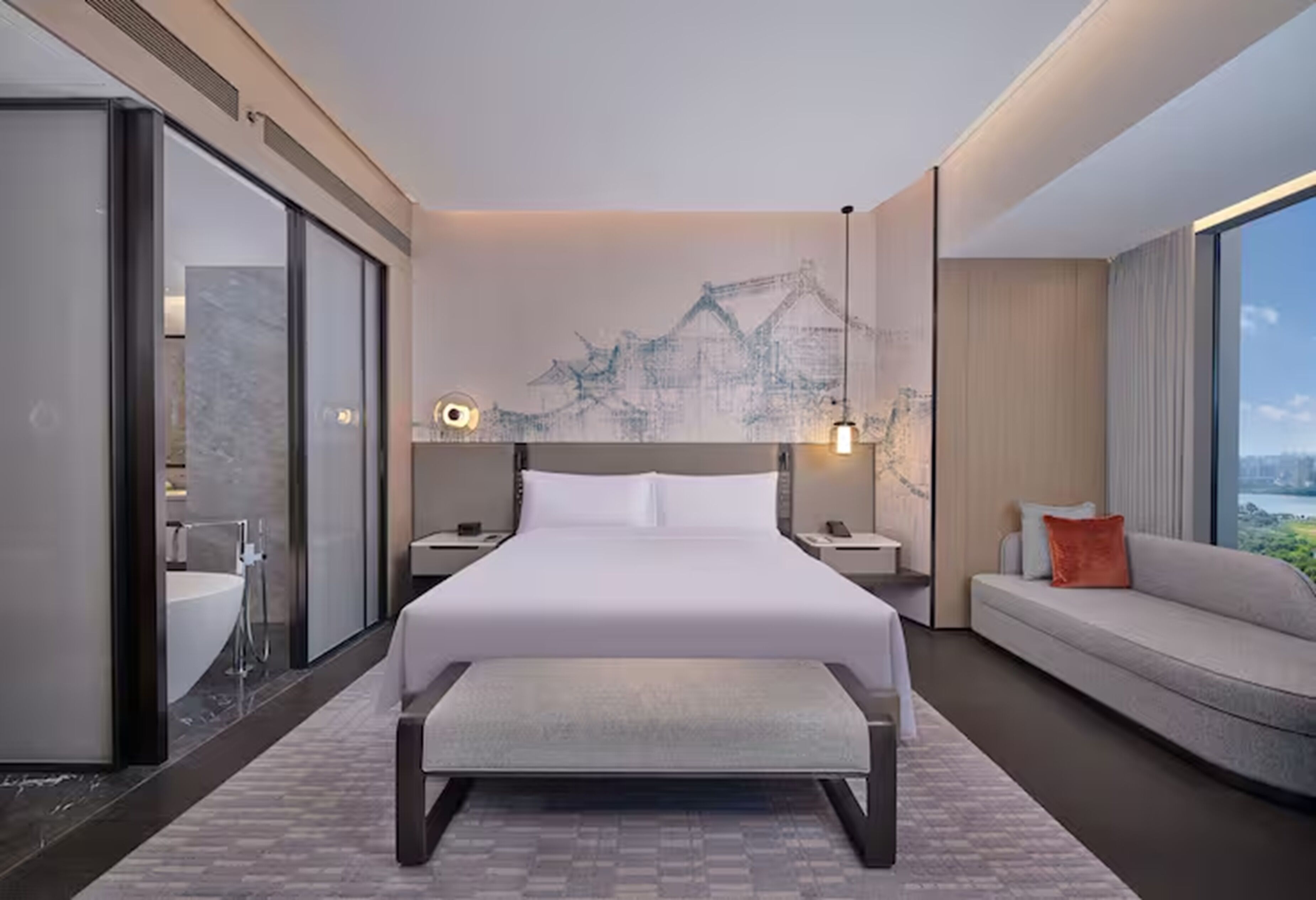 Una habitación de hotel moderna con una cama grande, un sofá, un banco, un baño con bañera y vistas a la ciudad.