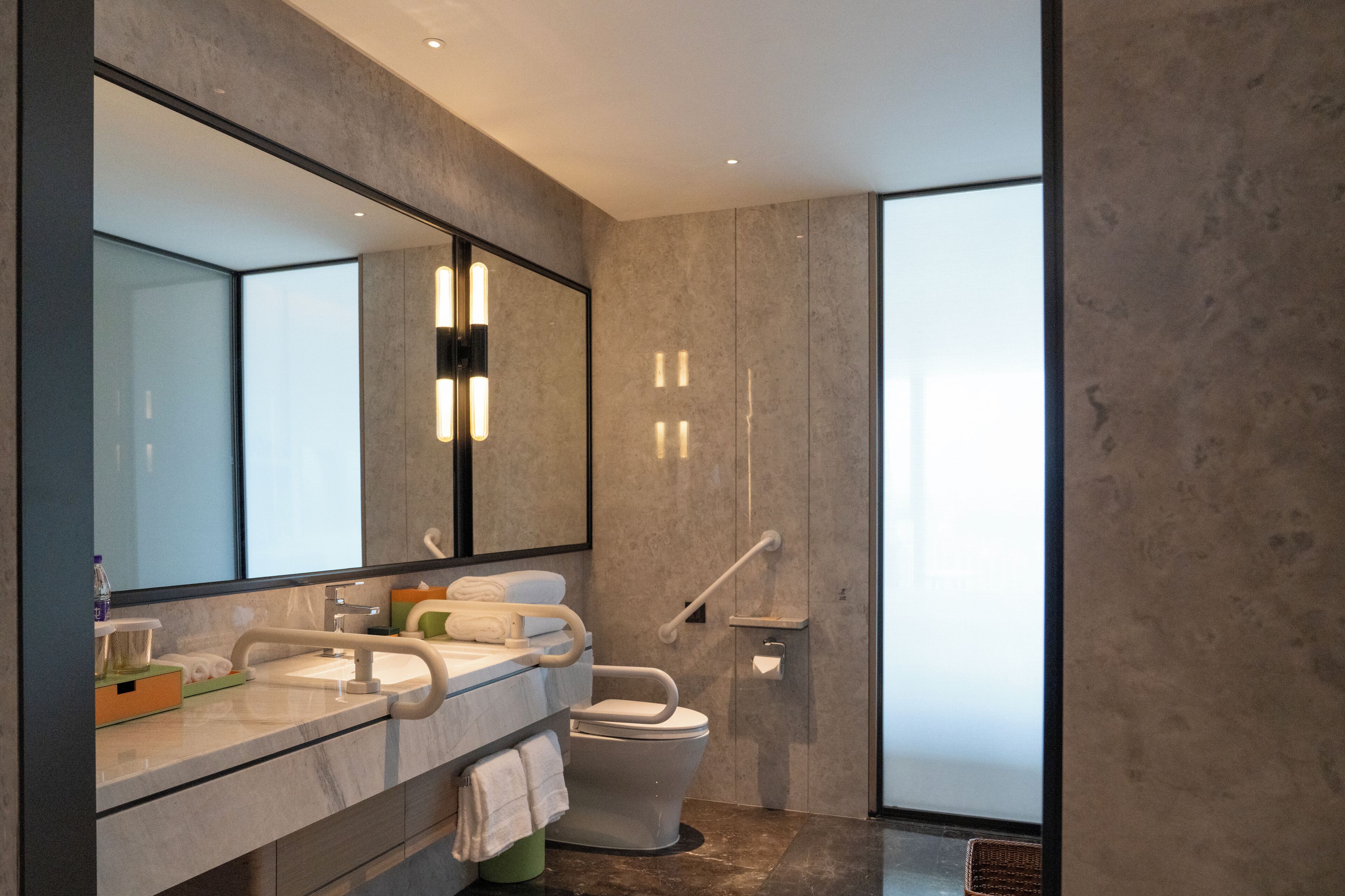 Un baño moderno con un espejo grande, un lavabo, un inodoro y una zona de ducha.