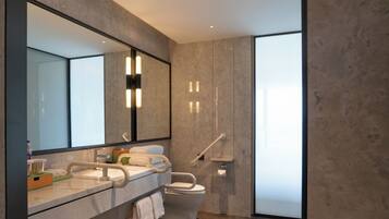 Un baño moderno con un espejo grande, un lavabo, un inodoro y una zona de ducha.