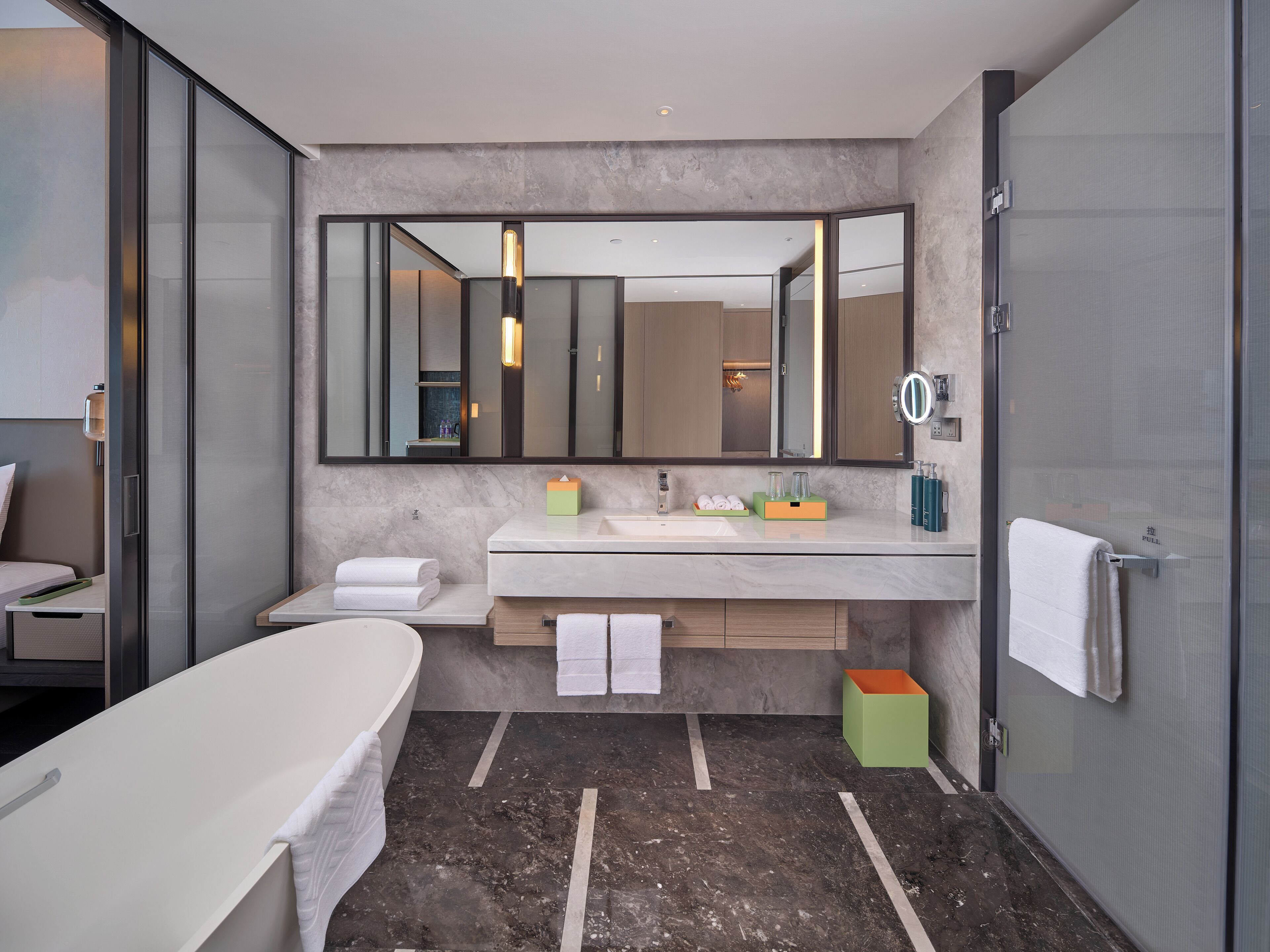 A modern bathroom with a large mirror, a bathtub, a vanity with a sink, and a shower area.