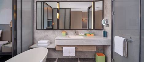 A modern bathroom with a large mirror, a bathtub, a vanity with a sink, and a shower area.