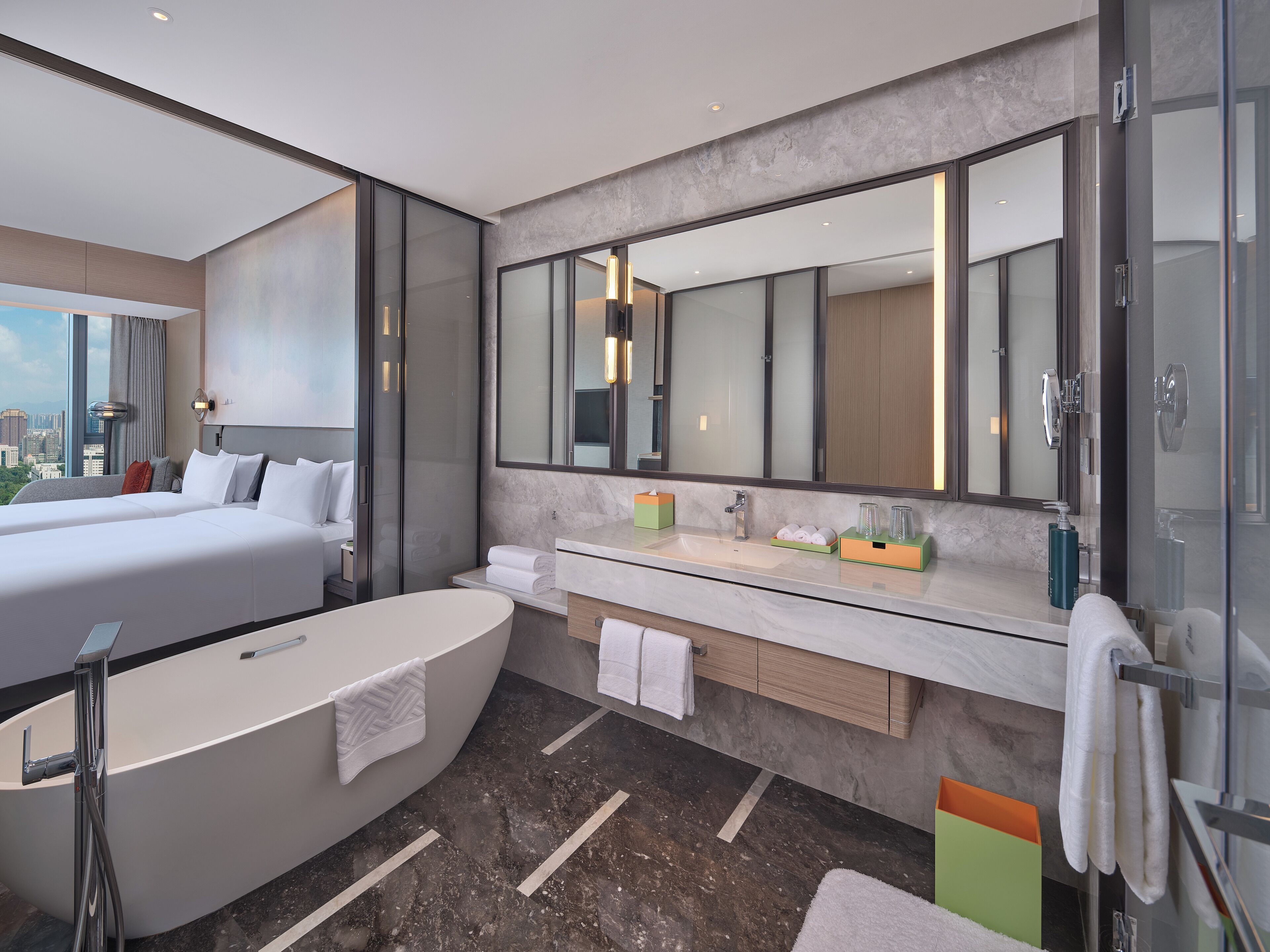 Un bagno d'hotel moderno con una grande vasca, un mobile toilette con uno specchio e vista sulla città.